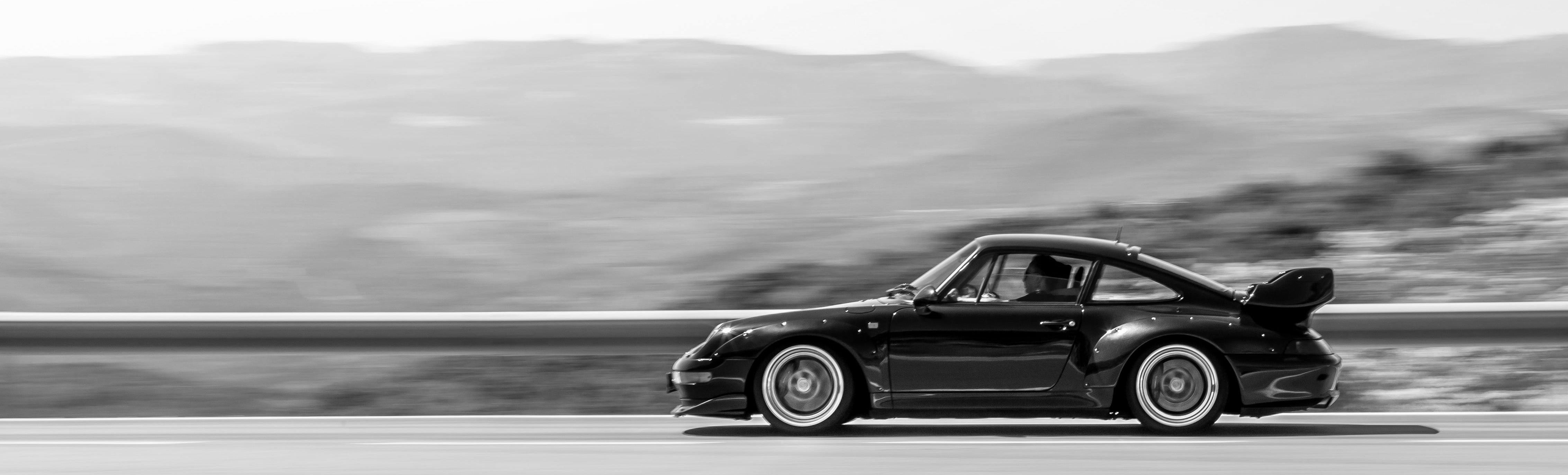 Black 911 sports car racing on a mountain road with blurred background